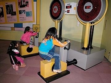 ペダルをこいで発電量を競う「発電装置」を体験する子どもの様子