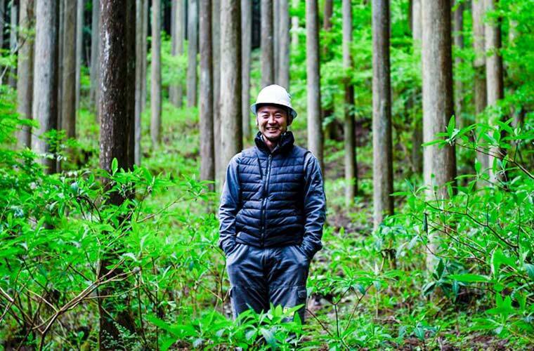 森林の中で立っている山田尚弘さんの写真