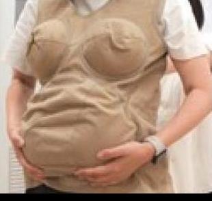ベージュの妊婦体験スーツを着て胸と腹部が強調され両手で腹部を支える人の様子
