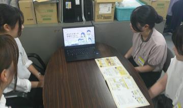 テーブルを囲んでノートパソコンと資料を見ながら打ち合わせをする学生