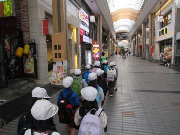 商店街を列を組んで歩いている児童の写真