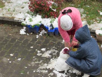 雪だるまを作っている子供の写真