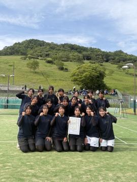 写真撮影で、屋外で女子ソフトテニス部員が集合している様子