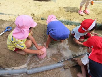 砂場に水をためて遊ぶ子供の姿