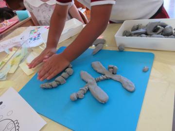 粘土でトンボをつくる3歳児