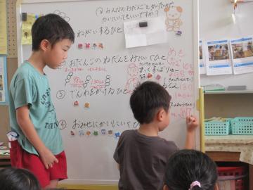 室内で調べたことをホワイトボードに書く5歳児たちの様子