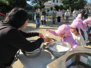 園庭でお米を量る4歳児たちの様子