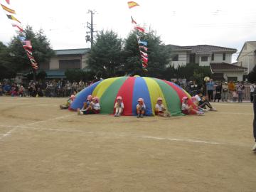 園庭で4歳児たちがパラバルーンの演技をする様子