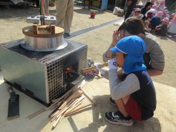 園庭で火吹き体験をする5歳児たちの様子