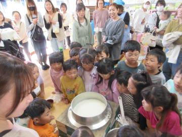 室内においてかまどで炊いたご飯を見守る園児たちの様子