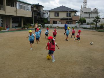 園庭でサッカーの試合に参加する園児たちの様子