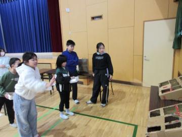 体育館で、8マスに穴の開いた90センチメートル角ほどの段ボール箱にボールを投げ入れようとする生徒たち