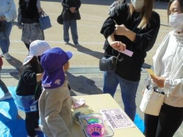 園庭で5歳児が金魚すくいの受付をしている様子