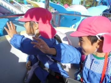 遊園地の乗り物に乗っている園児たちの様子