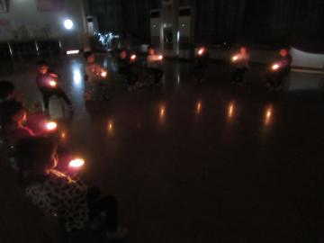 遊戯室内で消灯してキャンドルサービスする園児たちの様子