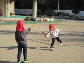 園庭で羽根つきをしている園児たちの様子