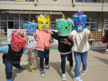 園庭で鬼のお面をかぶってポーズをする園児たちの様子
