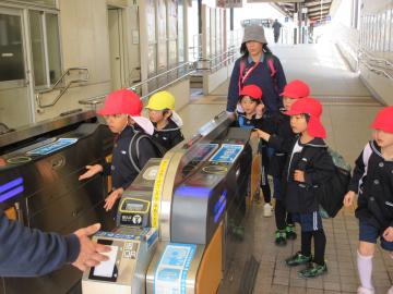駅の改札口で、園児たちが切符を入れている様子