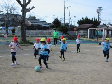 ボールを追いかけている子を後ろから皆がおいかけている