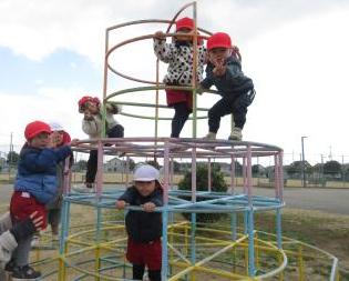 園庭で、3歳児がジャングルジムをしている様子