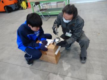 館内で生徒が錫の器づくりで熟練技能者から指導を受ける様子