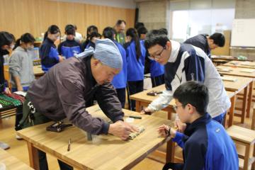 会場内で生徒が熟練技能者からミニ畳花台の作り方を教えてもらっている様子