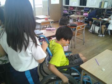 車椅子に座って車いす体験をする児童のようす