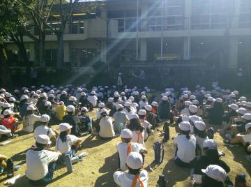 建物前の中庭に整列した生徒達が、体育座りをして退所式をしている写真