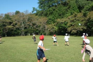 広い芝生の広場で紙飛行機大会をしている写真