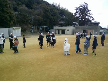 運動場で大縄跳びをするクラスメイトに対し、大きな声で声援している生徒たち