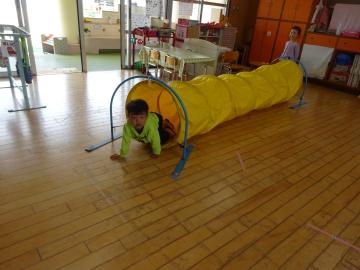 いちご組の部屋でトンネルで遊ぶ園児の様子