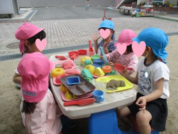 園児が砂場でごちそうを作って遊んでいる写真