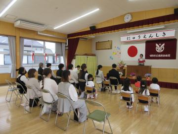 親子が遊戯室で入園式をしている写真