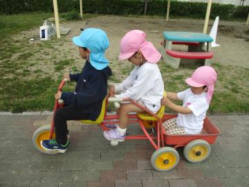三輪車に台車をつなげて乗る子供たち