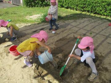 穴に水を流して遊ぶ子供