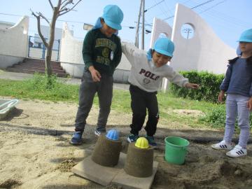 バケツで砂のプリンをつくる子供