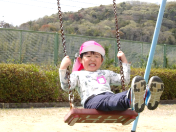 4歳児が笑顔でブランコに乗る様子