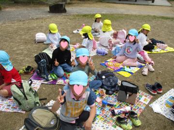 屋外で園児がお弁当を食べている様子