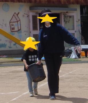 植木鉢を先生と運ぶ園児