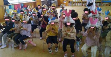 4歳児と5歳児が遊戯室で柏餅を食べている写真