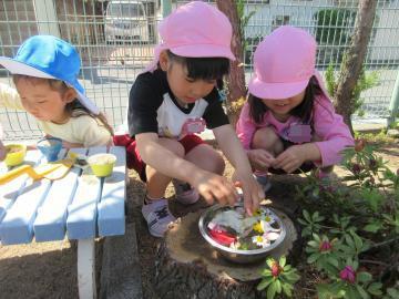 園庭で4歳児がパーティーのごちそうを作っているところ