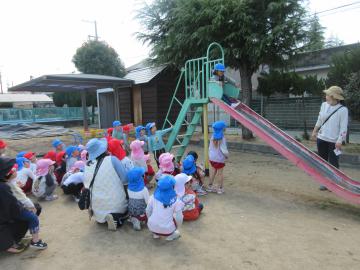 園庭で5歳児が3歳児と4歳児に遊具の遊び方を伝えているところ