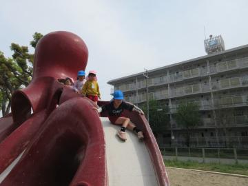 公園内で園児がたこの滑り台を滑っているところ