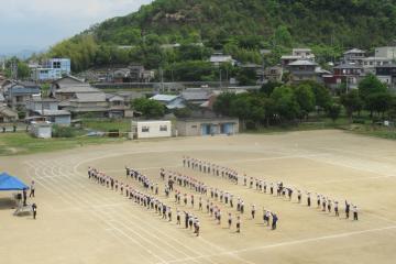 運動場で児童が3つ目の隊形を整えている様子