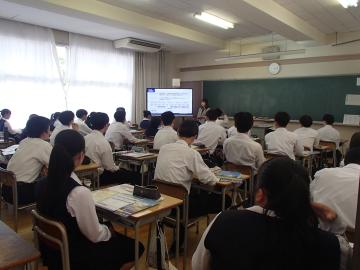 教室内で大学の説明会が開催される様子。生徒たちが着席し、説明を聞いています。