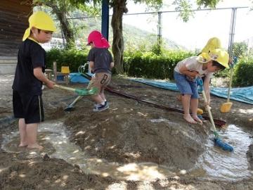 砂場で裸足になって泥んこ遊びをする様子
