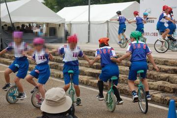 ステージの上と下に分かれて一輪車の演技をする様子