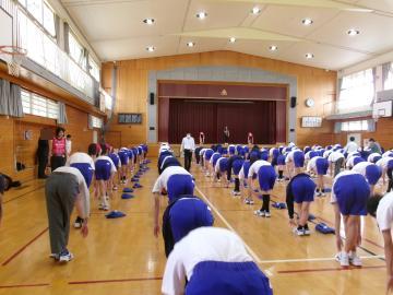 ヴィクトリーナのトレーナーさんの指導を受けながら、生徒が前屈のストレッチに取り組んでいます