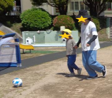 親子で手をつないで蹴りながらサッカーボールを運ぶ
