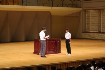 学校長が陸上部部長に激励をする様子